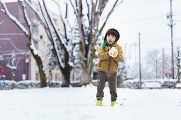 雪の公園で遊ぶ6歳の男の子
