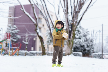 雪の公園で遊ぶ6歳の男の子