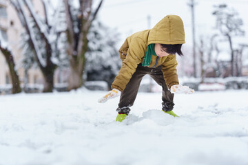 雪の公園で遊ぶ6歳の男の子