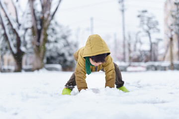 雪の公園で遊ぶ6歳の男の子