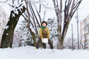 雪の公園で遊ぶ6歳の男の子