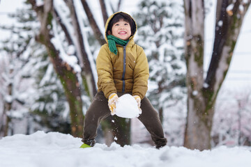 雪の公園で遊ぶ6歳の男の子