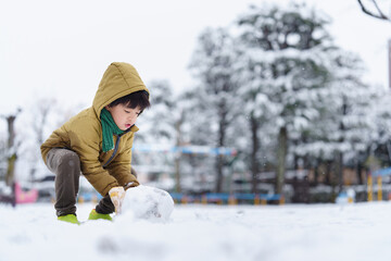 雪の公園で遊ぶ6歳の男の子