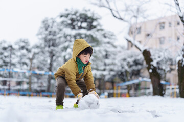 雪の公園で遊ぶ6歳の男の子