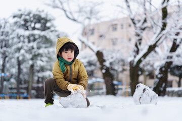 雪の公園で遊ぶ6歳の男の子