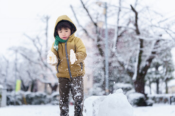 雪の公園で遊ぶ6歳の男の子