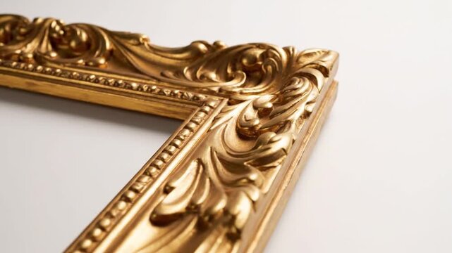Close-up of ornate, golden picture frame corner against white backdrop. Features detailed carvings