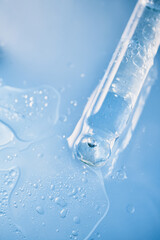 Pipette releasing transparent liquid with bubbles, splashing on light blue surface