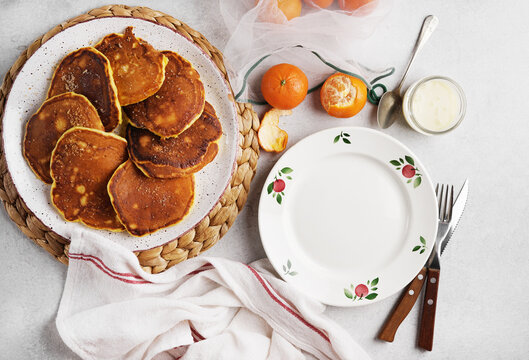 Delicious homemade tangerines pancakes with condensed sweet milk on a plate on the table, top view