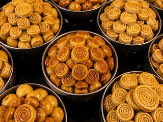 A collection of sweet pastries in metal bowls on a dark background