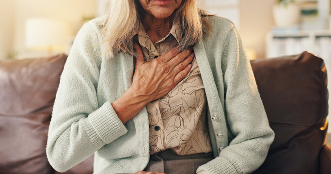 Old woman, chest pain and hand in home with heart attack symptoms, discomfort and cardiac problem. Senior person, medical issue and health crisis on sofa with angina, asthma and breathing difficulty.