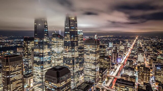 Night cityscape view with lit skyscrapers and street lights under a cloudy night sky
