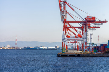 Fototapeta premium Industrial Gantry Cranes at Osaka Bay Harbor Port, Japan. Large container cranes at commercial shipping terminal in Osaka, highlighting global logistics, maritime trade, and industrial infrastructure.