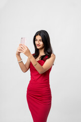 Naklejka premium young indian stylish woman taking selfie with smartphone standing on white background