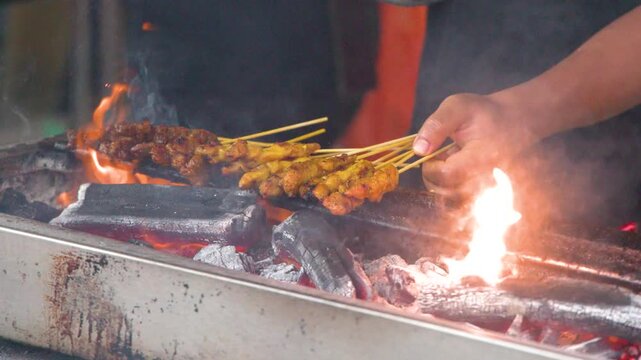 Asian Street Food Vendor Grilling Satay Over Charcoal Fire in Singapore