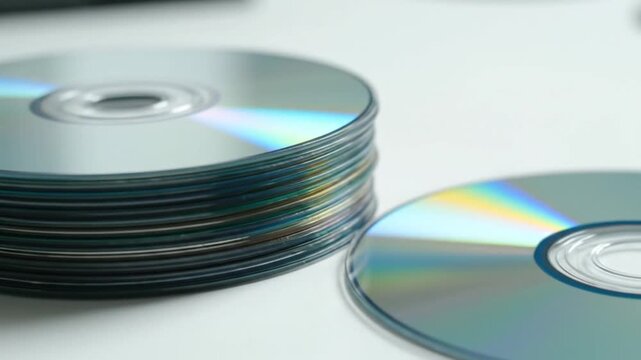 A stack of shiny discs rests on a white surface, with one disc separate. Close up view