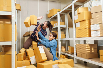 Asian adult women online business partners trying to control falling parcel box during order...
