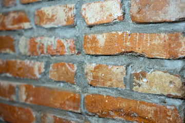 Fototapeta premium Close up of red brick wall with visible mortar joints and rough masonry texture, angled perspective construction background.