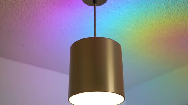 A cylindrical pendant lamp hangs from the ceiling, reflecting colorful light on the surface