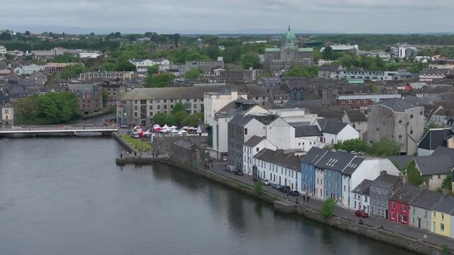 A scenic aerial shot of the famous Long Walk colorful houses and the Corrib River in Galway city center under a cloudy Irish sky. Perfect for travel documentaries and European tourism content.