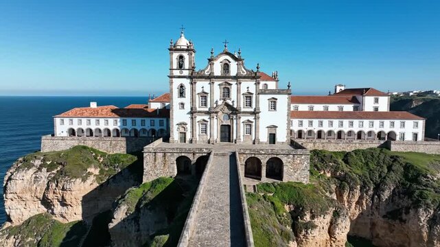 A grand white church atop a cliff, a stone pathway leading to its entrance, with clear blue sky