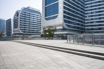 Fototapeta premium Modern curved glass facade office building complex with plaza and steps under clear sky