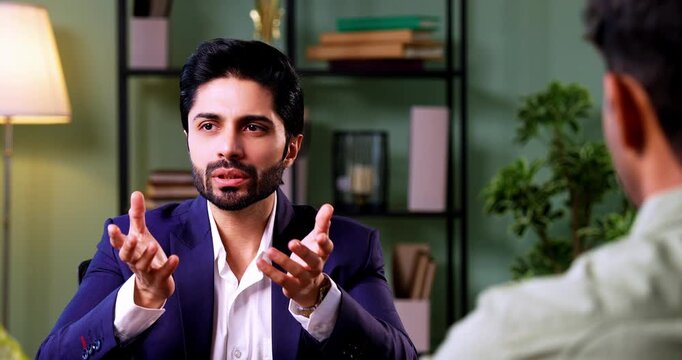 Indian couple visiting discussing with officer or executive shaking hands sitting across table after successful financial consultation and investment deal closure in modern corporate office interior