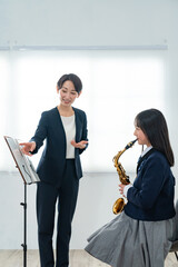 サックスのレッスンを受ける女子生徒と音楽教師