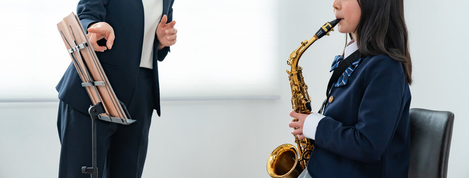 サックスのレッスンを受ける女子生徒と音楽教師