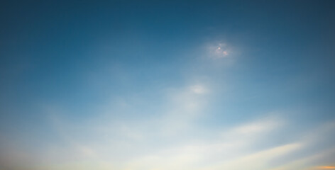 the evening sky is a beautiful blend. of blue sunlight and an orange horizon, with soft, fluffy clouds.