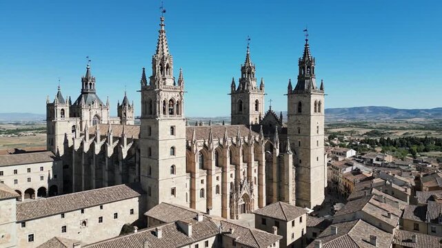 An aerial shot showcases a majestic gothic cathedral with towering spires, intricate details, and a clear blue sky