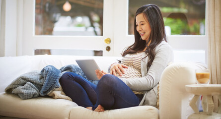 Obraz premium Relax, pregnancy and Asian woman with tablet in home, prenatal research or development app. Pregnant mom, tech and happy person on sofa in living room for maternal blog, bump update or kick counter