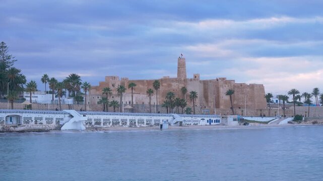Moody seascape at Monastir, Tunisia, the fort ribat and Mediterranean sea under dramatic storm clouds and soft light, conveying tranquility, travel mood, and coastal atmosphere