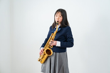 Fototapeta premium アルトサックスを持って笑顔の制服姿の日本人少女