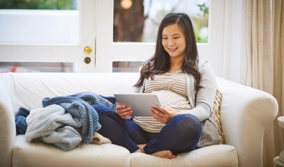 Relax, pregnancy and Asian woman with tablet on sofa, prenatal research or development app....