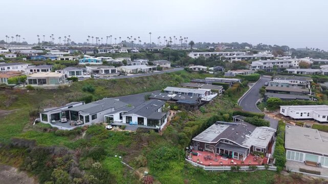 Drone video showcasing hilltop homes above Zuma Beach in Malibu, California. The aerial footage reveals luxurious residences and natural landscapes on an overcast day.