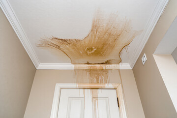 Water stains mark the ceiling of a tired hallway