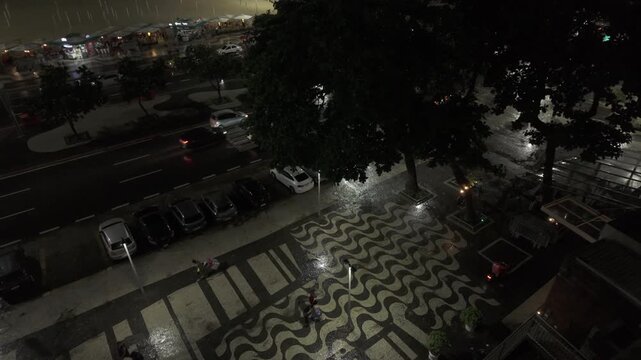 Tilt-down night view of the iconic Copacabana sidewalk wet from rain
