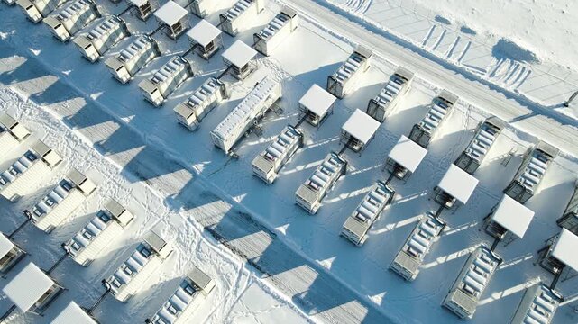 Low-altitude winter aerial glides above containerized battery units, revealing high-voltage infrastructure, snowy geometry, and the scale of Estonia&rsquo;s flagship energy storage site.
