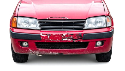 Damaged front of an older, red car with faded paint and a cracked bumper against a stark white background