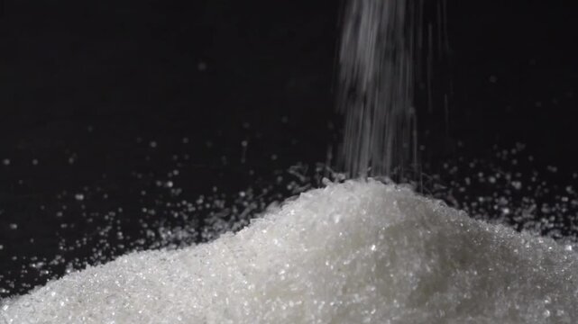Pouring granulated sugar to form a crystalline pile on a textured surface