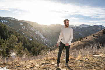 Naklejka premium Young man hiking on a mountain ridge at sunset