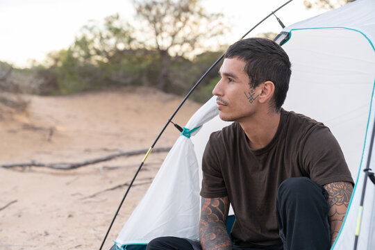 Young man camping outdoors contemplating nature in desert