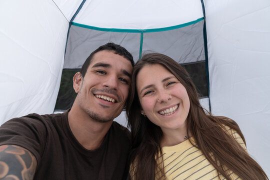 Happy couple enjoying travel vacation taking selfie inside tent