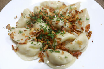 Freshly cooked dumplings with dill and fried onion