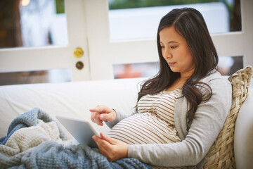 Obraz premium Tablet, typing and reading with pregnant woman on sofa for baby research, prenatal care app and social media. Motherhood blog, scroll and online pregnancy forum with person in living room of home