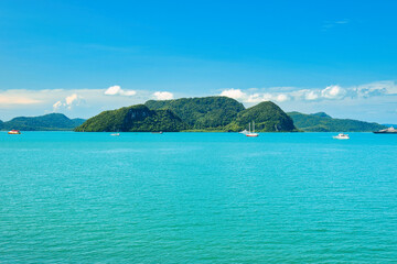 Fototapeta premium A beautiful view of Langkawi island against a beautiful blue sky with some boats in the distance on the horizon. Tropical scenery. located at Kedah, Malaysia - September 25 2024:
