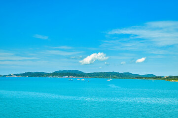 Fototapeta premium A beautiful view of Langkawi island against a beautiful blue sky with some boats in the distance on the horizon. Tropical scenery. located at Kedah, Malaysia - September 25 2024: