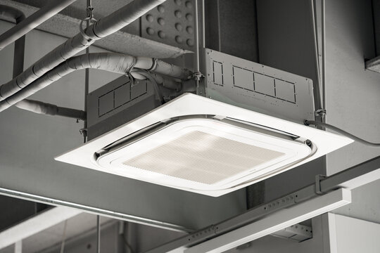 Ceiling-mounted square cassette air conditioner with ventilation grille and exposed ductwork