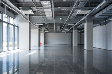 Spacious modern office shell space with exposed ceiling infrastructure and reflective tiled floor